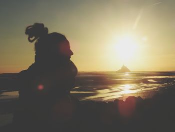 Silhouette woman standing at beach against sky during sunset. mont saint michel 