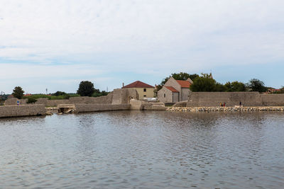 Houses by lake against building against sky