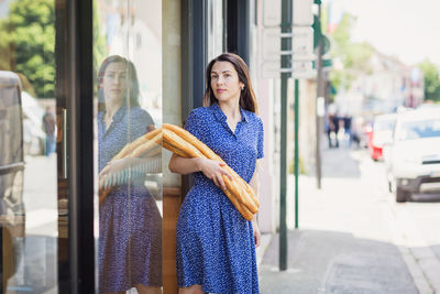 Young woman buying a french baguette