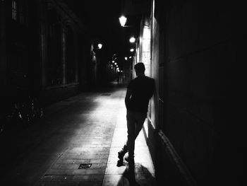 Rear view of man standing by wall at night