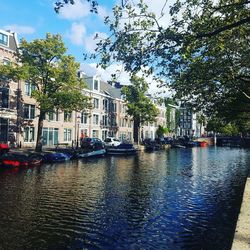 Boats moored on river in city against sky