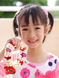 Close-up portrait of smiling cute girl holding floral garland