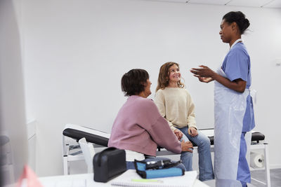 Female doctor talking to girl patient and mother during appointment