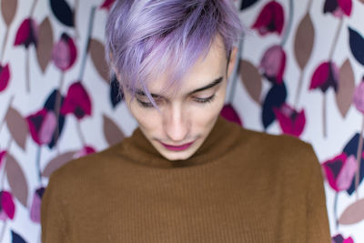 Close-up of homosexual man standing against curtain