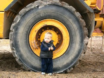 Boy standing by tire on field