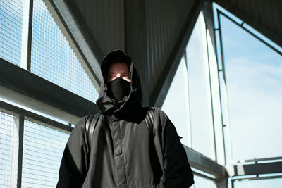 Man looking away while standing against window