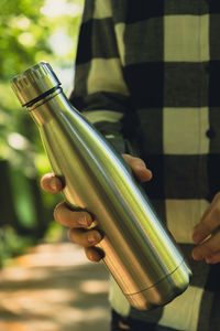 Close-up of unrecognizable female hand holding water bottle. reusable steel thermo water bottle in