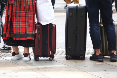 Low section of women with suitcases standing on road