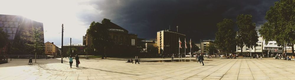 People on street amidst buildings in city against sky