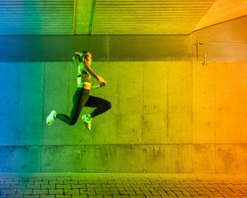 Woman jumping in front of wall