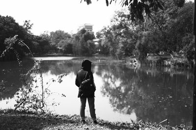 Rear view of woman standing at lake against sky