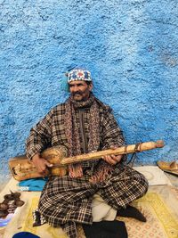 Man sitting against blue wall