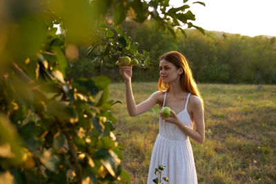 Young woman standing against plants