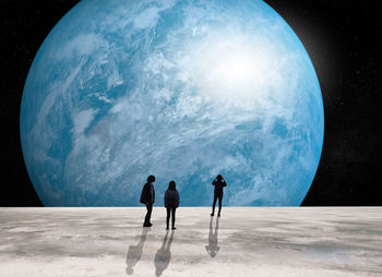 Digital composite image of people standing moon looking at blue planet