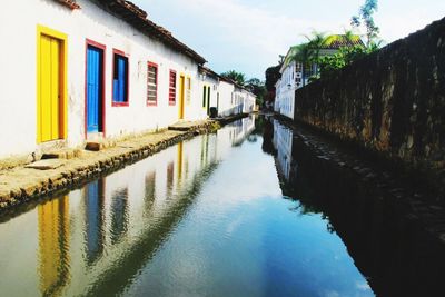 Canal amidst houses against sky