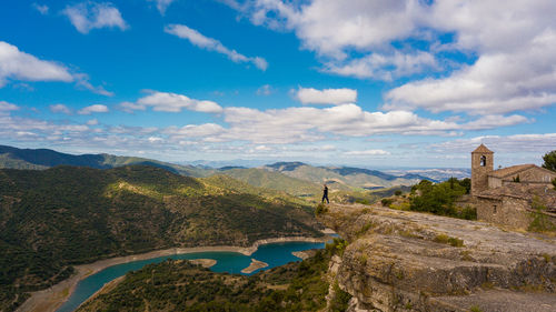 Man standing on cliff by mountains against sky at siurana