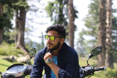 Young man wearing sunglasses against trees