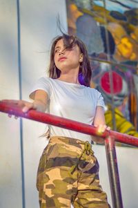 Young woman looking down while standing against wall