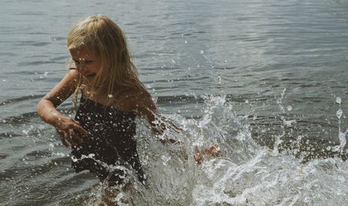 High angle view of happy girl splashing water in sea