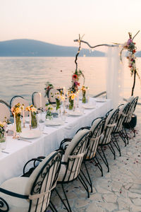 Chairs and table on beach by sea against sky