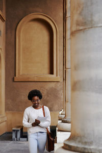 Portrait of smiling woman standing against wall