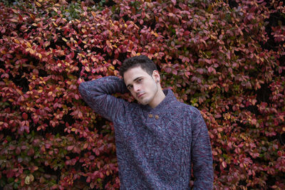 Portrait of young man standing by flowering plants