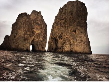 Rock formation by sea against sky