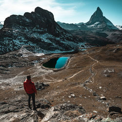 Rear view of man standing on landscape by mountain against sky