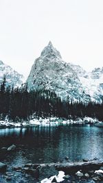 Scenic view of lake by snowcapped mountain against sky