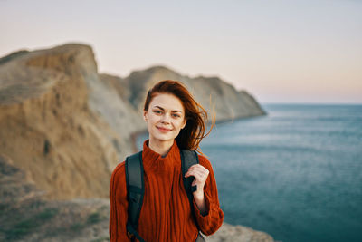 Portrait of smiling woman standing against sea