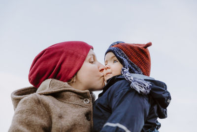 Low angle view of mother with son against clear sky