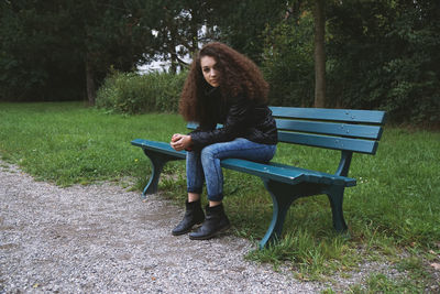 Portrait of woman sitting on bench at park