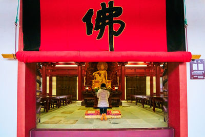 Rear view of woman with red umbrella walking in entrance