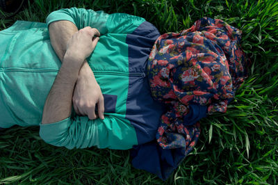 Directly above shot of man with face covered by textile lying on grassy field