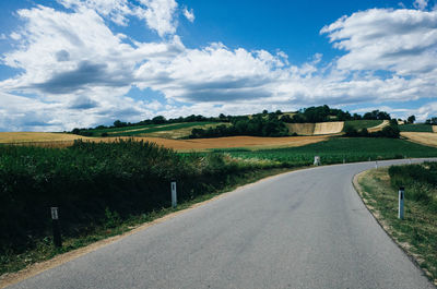 Road amidst field against sky