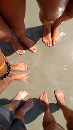 Low section of people and their feet standing on beach