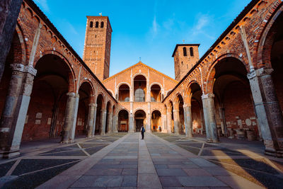 Wide view of the basilica of sant'ambrogio with a tourist in the center of the courtyard