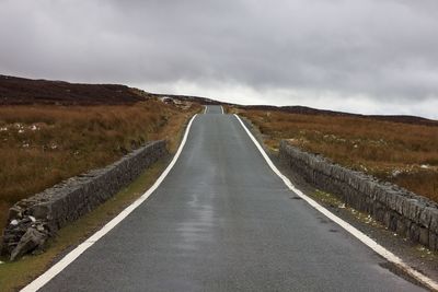 Empty road along landscape against sky