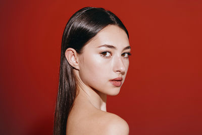 Portrait of young woman against yellow background