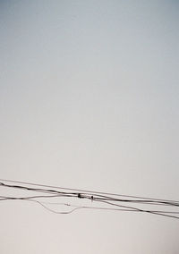 Low angle view of power cables against clear sky