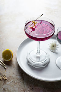 From above transparent elegant glass filled with blackberry liqueur with ice and lemon slice placed on table