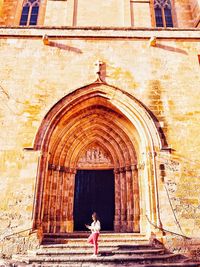 Full length rear view of woman walking in temple outside building