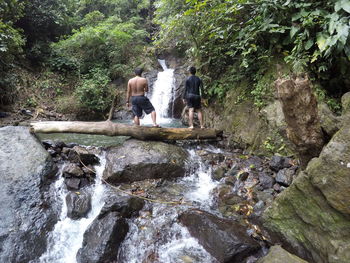 Man standing by waterfall in forest