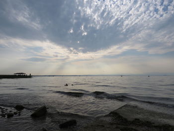 Scenic view of sea against cloudy sky during sunset