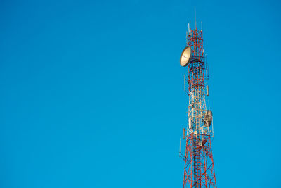 Low angle view of communications tower against blue sky