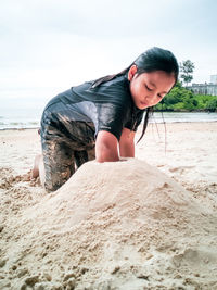 A young girl is playing with sand on beach. vacation concept.