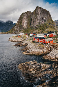 High angle view of houses on rock formation by river against cloudy sky