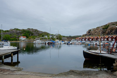 Boats moored at harbor against sky