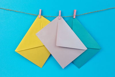 Close-up of multi colored paper hanging on blue wall