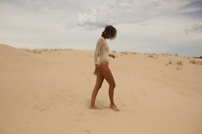 Side view of young woman walking on sandy beach